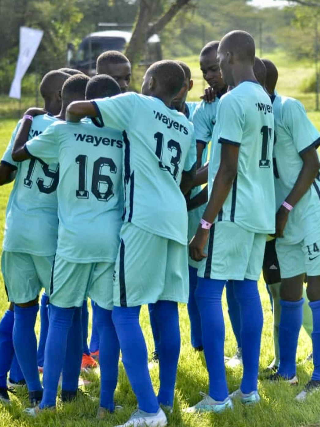 Football team in Wayers jerseys huddled together before a match