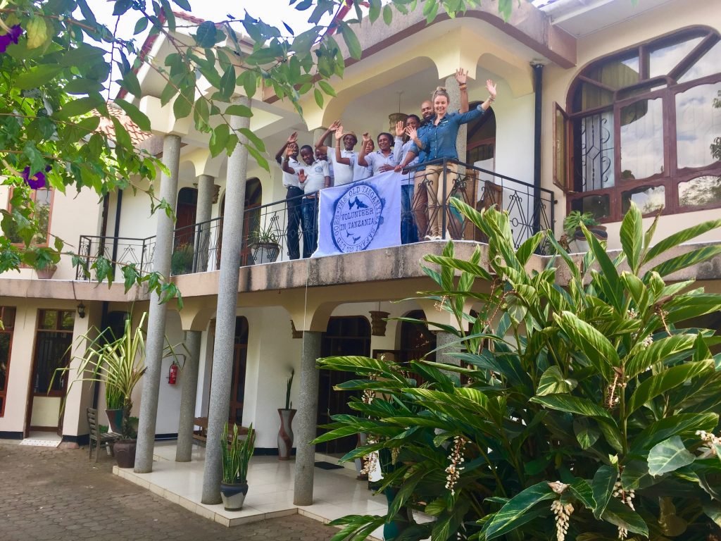 Volunteer in Tanzania team waving from the balcony of the VIT Arusha House