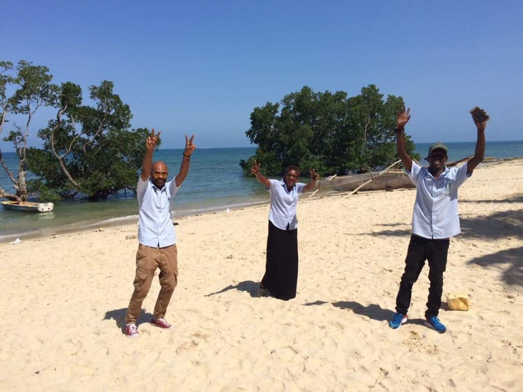 Zanzibar team members celebrating on the beach with blue ocean behind them