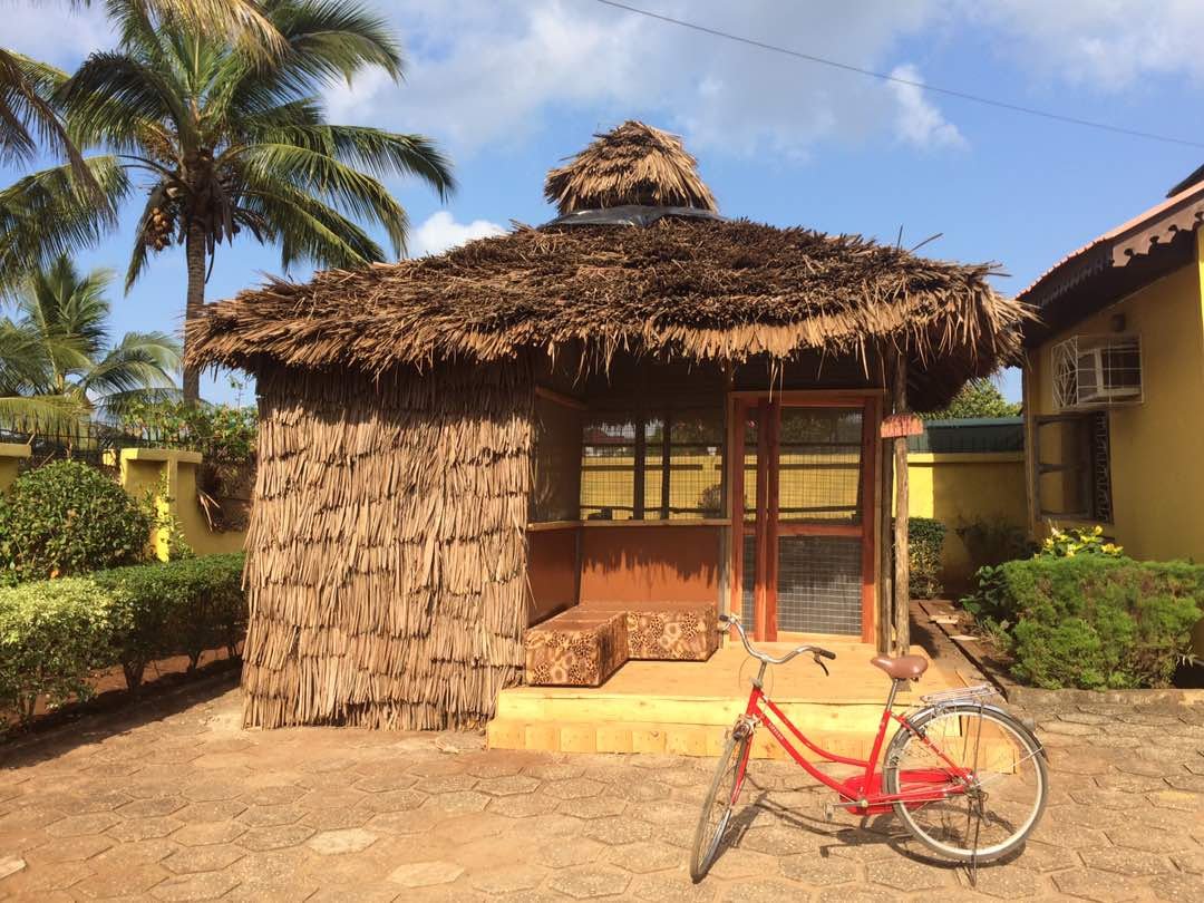 Thatched patio with palm trees and bicycle at the Pink Mansion in Zanzibar